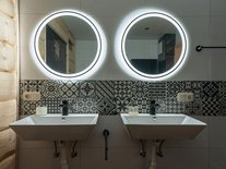 Das Badezimmer in modern-rustikalem Stilmix ist mit zwei Waschbecken, einer Regendusche und Badewanne ausgestattet.