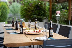 Überdachte Gartenterrasse mit modernem Holztisch, gedeckt für sechs Personen, im Grünen. Ideal für Urlaub, Ferienwohnung oder Sommerabende im Freien. Chalet Au in Fischen im Allgäu bei Oberstdorf.