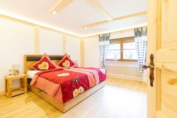 Zimmer-Bergzauber,helles Schlafzimmer mit Boxspringbett, rustikalen Holzelementen und moderner Einrichtung.