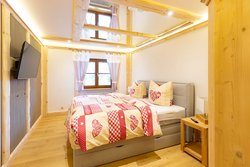 Zimmer-BergZeit, hochwertig eingerichtetes Doppelzimmer mit TV, Spiegel an der Decke, Holzfußboden und Blick auf das Fenster