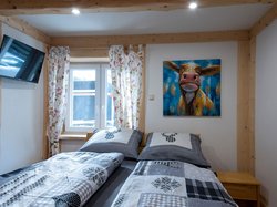 Next to the equally comfortable double bed under the bright window, there is a separate TV and of course a wardrobe. 