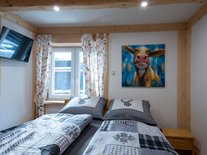 Neben dem ebenso bequemen Doppelbett unter dem hellen Fenster gibt es einen eigenen Fernseher und natürlich einen Schrank. 